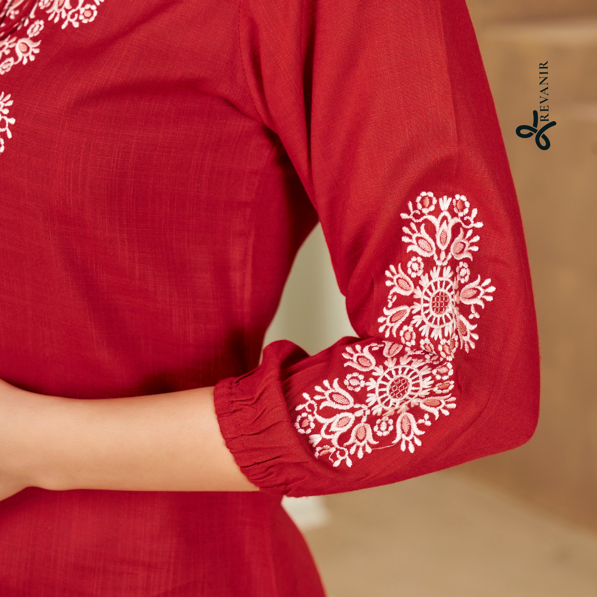Close-up of Revanir deep maroon commuter tunic showing intricate white floral embroidery on the sleeve and fabric finish